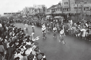 写真:1952年6月4日の第1回大会で、詰め掛けた観衆の拍手と歓声に送られながら国鉄仙台駅前から出発する選手たち