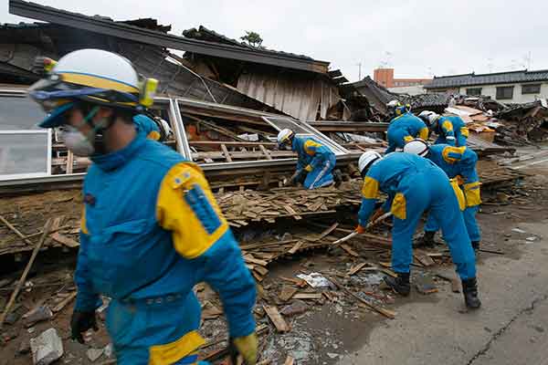 新潟県柏崎で 17日、倒壊した家屋のがれきの下から生存者を捜す警官。新潟県中越沖地震で少なくとも9人が死亡し、900人以上が負傷した。被災地では1万人以上が避難所で過ごした。