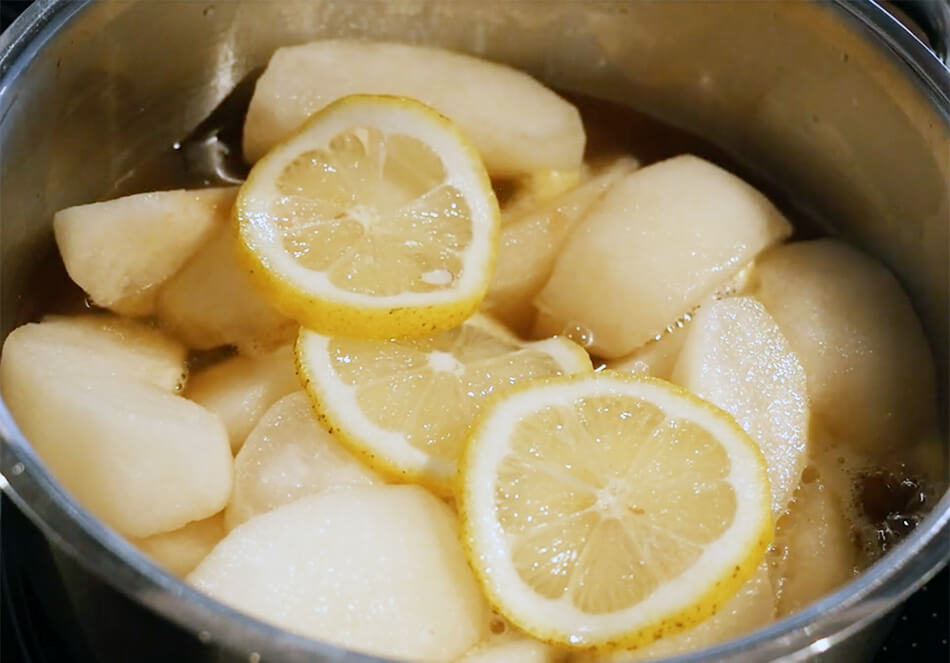 鍋に水、てんさい糖、はちみつ、梨、レモンの輪切りを入れ、煮立ててから、アクを取り、弱火にし、10分ほど煮る